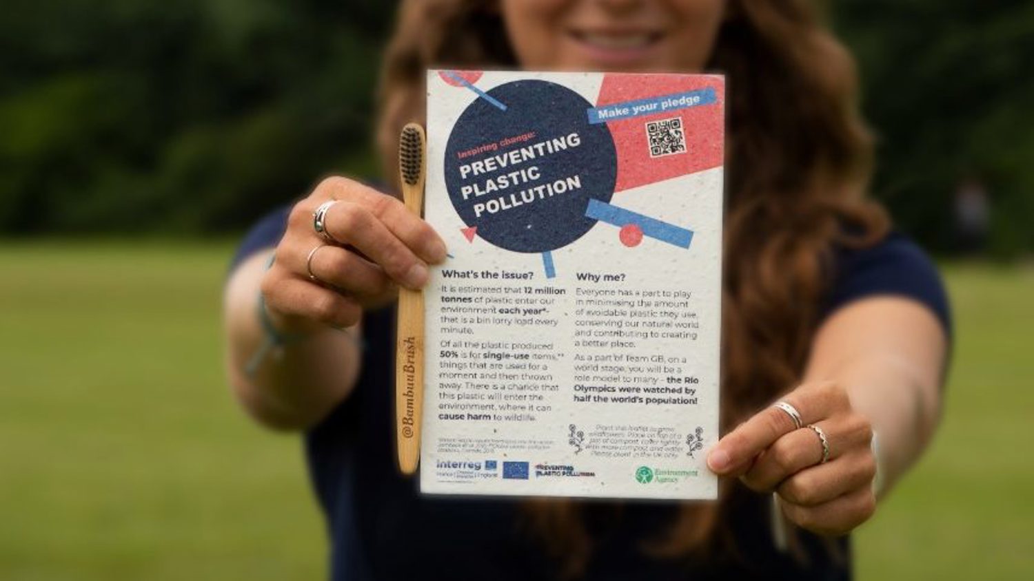 A person holds out a flyer titled "Preventing Plastic Pollution." The background features a grassy field and trees. The flyer includes text, a QR code, and graphics related to environmental awareness.