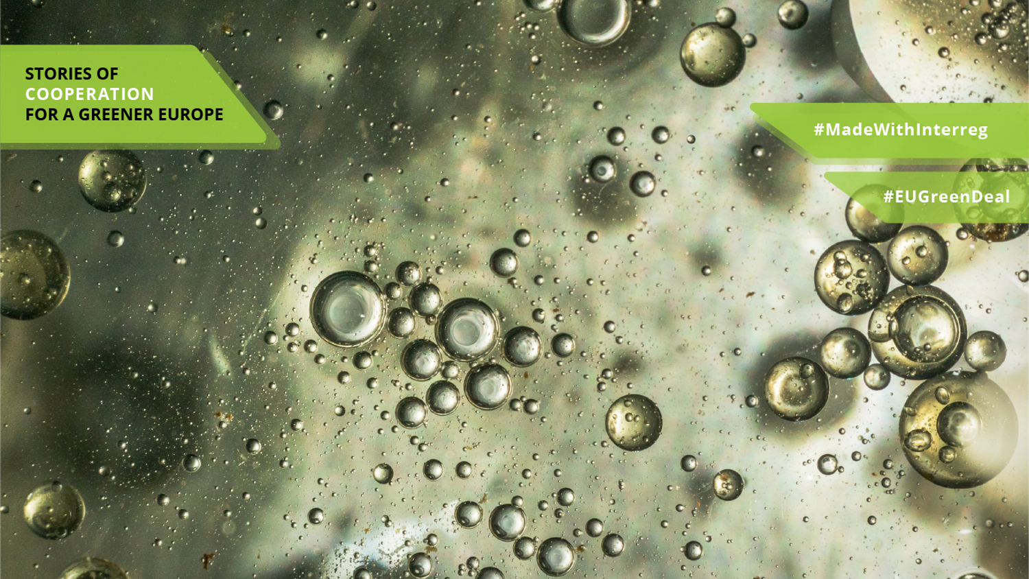 Close-up of bubbles floating in a green liquid with two green labels reading "Stories of Cooperation for a Greener Europe," "#MadeWithInterreg," and "#EUGreenDeal" overlaid on the image.