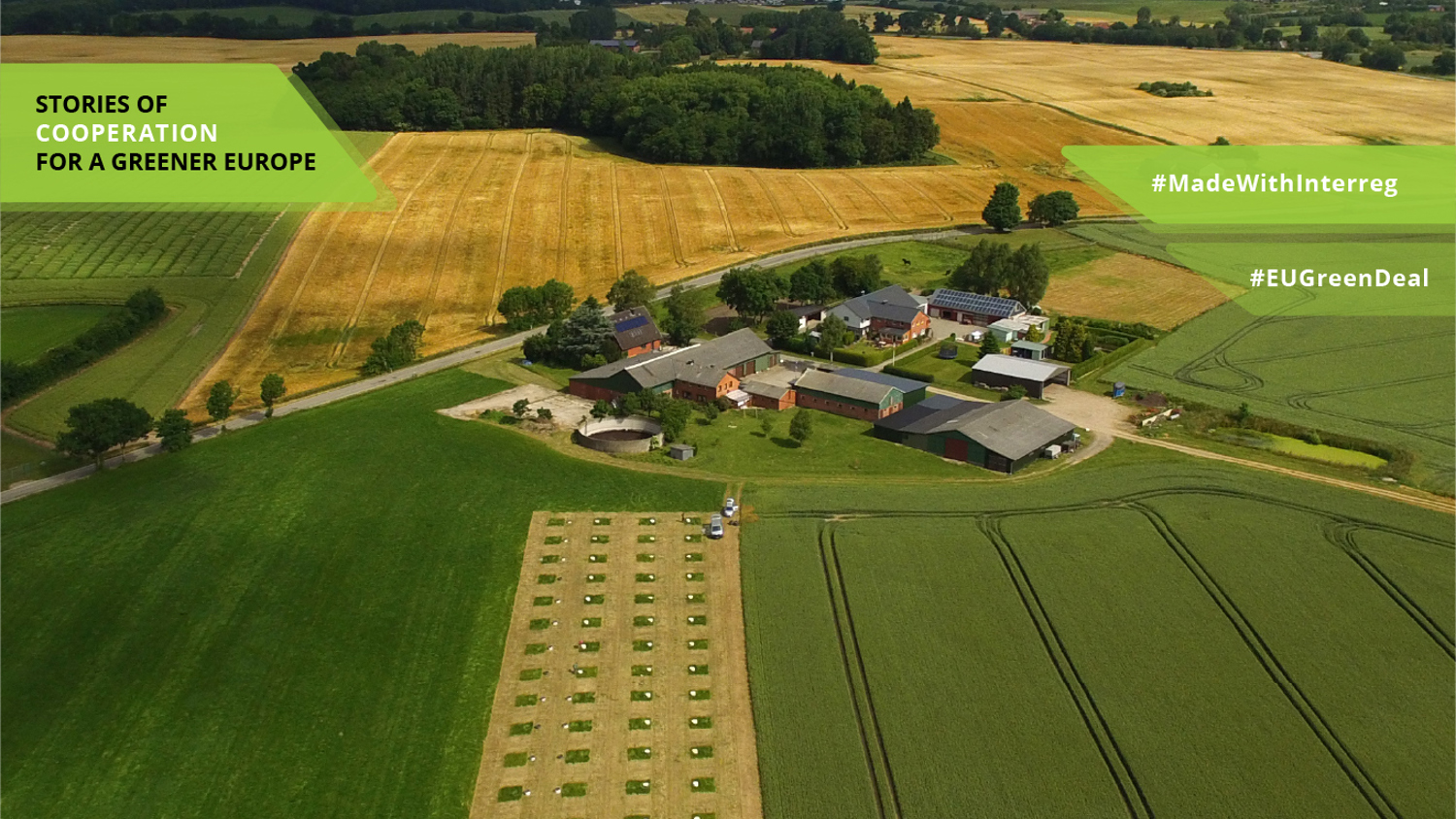 Aerial view of a rural landscape with fields and a cluster of buildings. Text overlay reads "Stories of Cooperation for a Greener Europe," "#MadeWithInterreg," and "#EUGreenDeal." The fields are lush and green, with a distant water body visible.