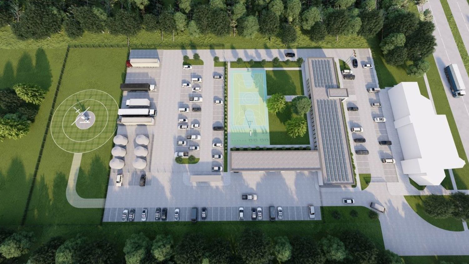 Aerial view of a facility with parking lots, a basketball court, several buildings, parked cars, buses, a helipad with a helicopter, and surrounding greenery.