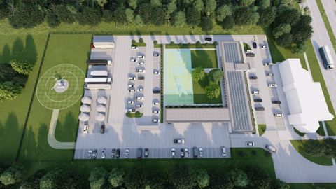 Aerial view of a facility with parking lots, a basketball court, several buildings, parked cars, buses, a helipad with a helicopter, and surrounding greenery.